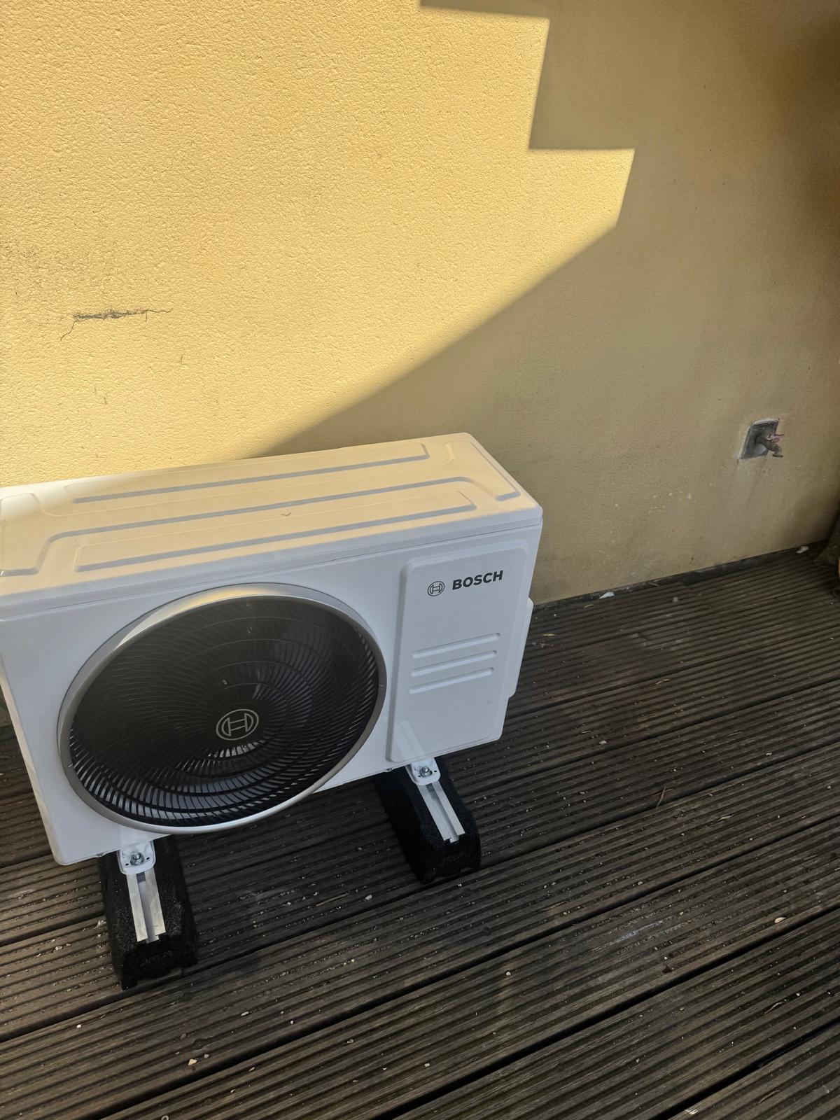 Unité extérieure de climatisation posée sur supports anti-vibrations sur une terrasse à Bruxelles